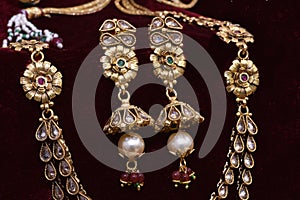 Gold plated Jewelry - Designer golden neck-set and earrings closeup macro image on red background