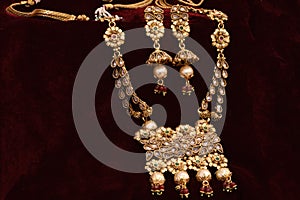 Gold plated Jewelry - Designer golden neck-set and earrings closeup macro image on red background