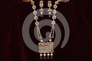 Gold plated Jewelry - Designer golden neck-set and earrings closeup macro image on red background