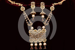 Gold plated Jewelry - Designer golden neck-set and earrings closeup macro image on red background