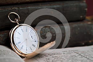 Gold pocket watch Pavel Bure on a gold pendant. Royal Russia. pocket watch on a dark background with books.