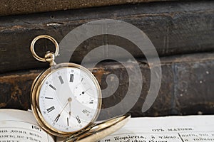 Gold pocket watch Pavel Bure on a gold pendant. Royal Russia. pocket watch on a dark background with books.