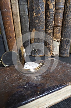 Gold pocket watch Pavel Bure on a gold pendant. Royal Russia. pocket watch on a dark background with books.