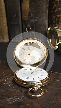 Gold pocket watch Pavel Bure on a gold pendant. Royal Russia. pocket watch on a dark background with books.