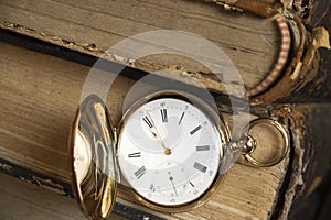 Gold pocket watch Pavel Bure on a gold pendant. Royal Russia. pocket watch on a dark background with books.