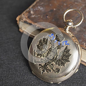 Gold pocket watch Pavel Bure on a gold pendant. Royal Russia. pocket watch on a dark background with books.