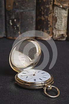Gold pocket watch Pavel Bure on a gold pendant. Royal Russia. pocket watch on a dark background with books.