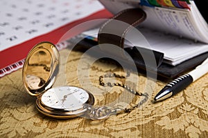 Gold pocket watch and a wall calendar and sketchpad