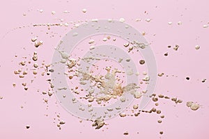 Gold potal drops and splashes on pale pink paper. Creative background photo