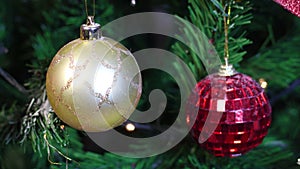 Gold and red Christmas ornaments on Christmas tree with blinking lights