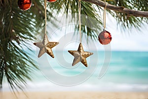 Gold and red Christmas ornaments on tropical beach. Christmas toys handing on a palm tree against exotic tropic sand beach. Happy