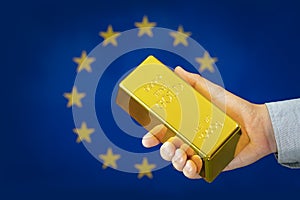 gold reserve of the european union concept. Gold bar in hand on european flag background