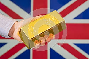 gold reserve of the Great Britain concept. Gold bar in hand on Great Britain flag background