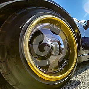 Gold rim and black spokes on a black cars wheels