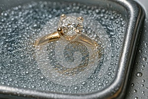 A gold ring with a brilliant diamond is immersed in a cleansing solution during a jewelry cleaning process