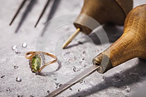 Gold ring with precious stones on the table, surrounded by jewelry repair tools