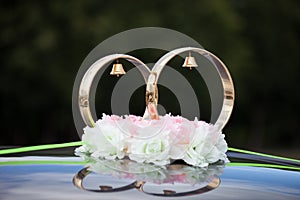 Gold rings and rose flowers on wedding car