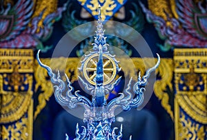 Gold rowel, the symbol of buddhist religion on the Thai blue art style pole with temple background