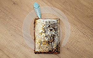 Gold sequin notebook with pen on a wooden