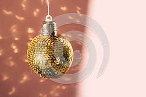 Gold shiny balls with sequins on a pink background.