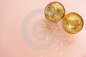 Gold shiny balls with sequins on a pink background.