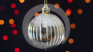 Gold shiny Christmas ornament swing with blinking lights behind