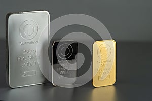 Gold and silver bars of various weights on a dark background.