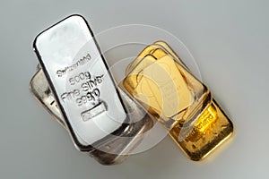 Gold and silver bars of various weights on a grey background