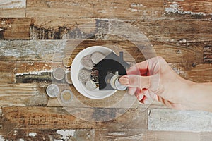 Gold and silver coins in the white ceramic plate in a hands of woman