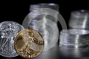 Gold and silver one ounce coins infront of stacks of silver coins