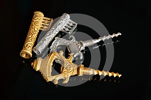 Gold and silver vintage corkscrews in the form of a key on a black background