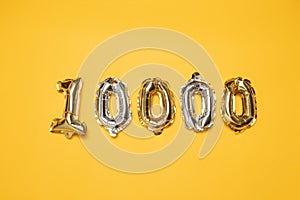 Gold and silvr 10,000 number balloons on a yellow background. Followers and Subscription Concept