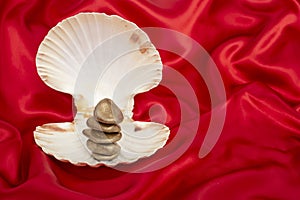 Gold sones stack in a seashell on red satin background photo