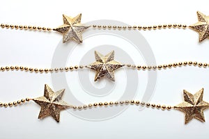 Gold star and bead garland on white backgroun. Flat lay.  Top view