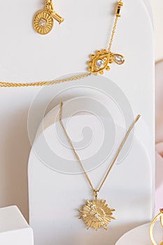 Gold star shaped and other necklaces on white jewelry display stands. Girl accessories