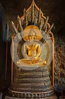 Gold statue of Buddha in Meditation with Naga Snake in Buddhist cave temple Wat Tham Suwankhuha Monkey Cave in Phang Nga Thailand