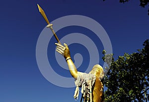 a gold statue of a warrior holding an arrow and spear