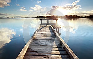 Gold sunshine over wooden pier on big lake