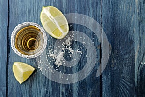Gold tequila in glass glass with salt and lime on a blue wooden background. bar. alcoholic beverages. view from above. with space