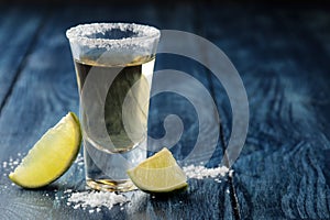 Gold tequila in glass glass with salt and lime close up on blue wooden background. bar. alcoholic beverages. place for text