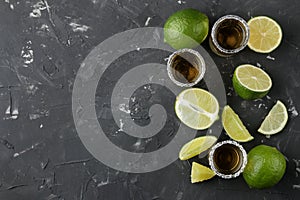 Gold tequila in a glass shot glass with salt and lime on a black concrete background. bar. alcoholic beverages. top view with spac