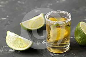 Gold tequila in a glass shot glass with salt and lime close up on a black concrete background. bar. alcoholic beverages