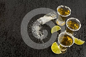 Gold tequila with lime on black background, top view