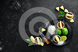 Gold tequila with lime and salt on black stone background. Top view.