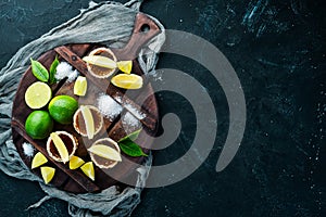 Gold tequila with lime and salt on black stone background. Top view.