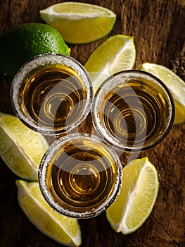 Gold tequila shot with lime on wooden background