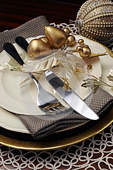 Gold theme Christmas dinner table setting. Close up on cutlery and plates