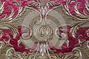 a gold thread decoration in a magenta cassock