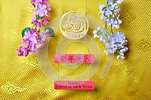 Gold tiger symbol and branches of white and pink sakura cherry blossom on yellow fabric with traditional chinese ornament with