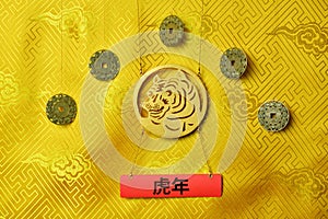 Gold tiger symbol, five lucky coins with chinese zodiac on yellow fabric with traditional chinese ornament with clouds. Chinese